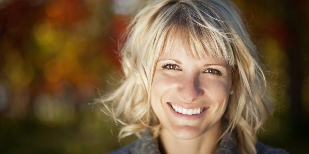A blonde woman smiling with porcelain veneers.