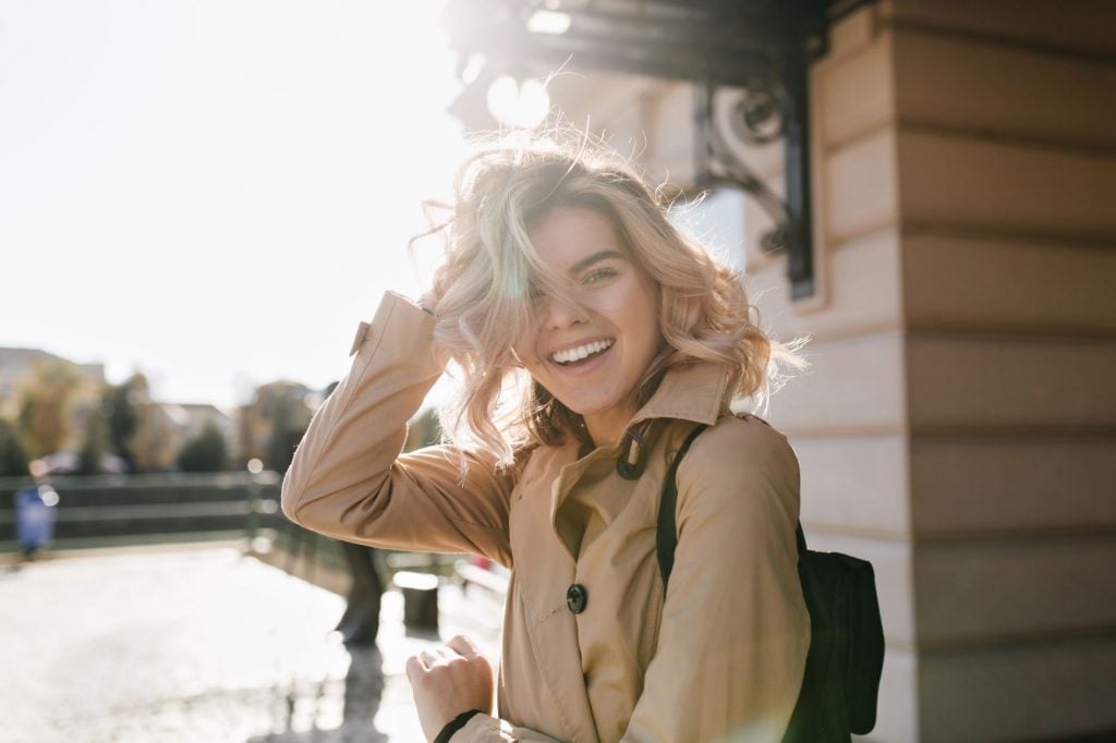 A blonde woman smiling with straight teeth from orthodontic treatment.