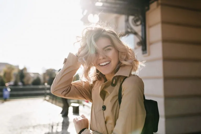 A blonde woman smiling with straight teeth from orthodontic treatment.