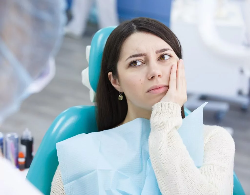 Woman in the dentists chair explaining her tooth pain to her Boulder emergency dentist